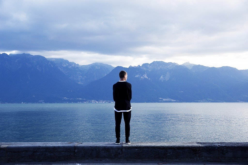 Man standing on dock looking over blue water