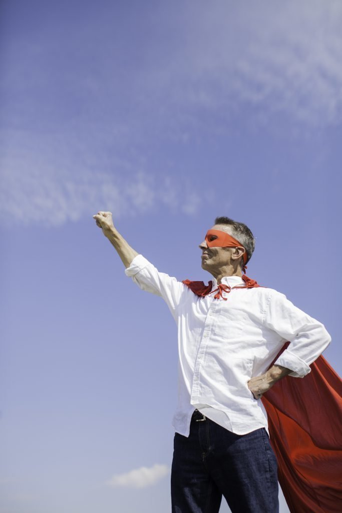 man posing as superhero with cape and maskspace for textlightstockvertical