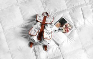 Backpack and recipe book on white bed